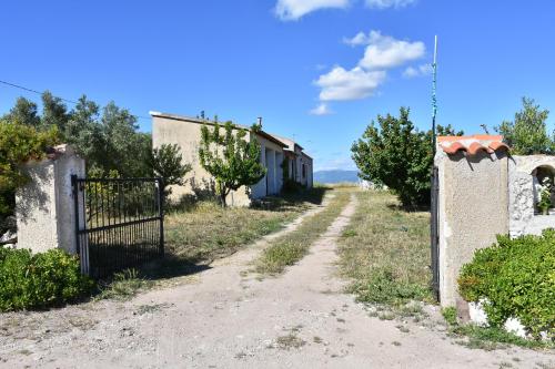 a dirt road with a gate in front of a house at Su Cuile historical country house with barbecue in Martis