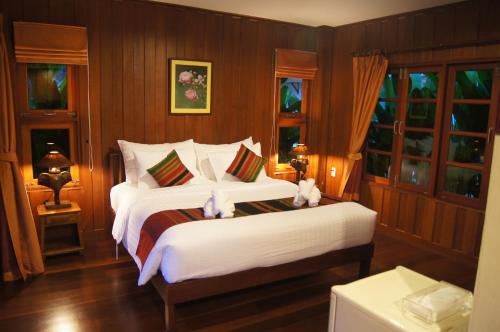 a bedroom with a bed with two stuffed animals on it at Maikaew Damnoen Resort in Damnoen Saduak