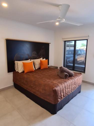 ein Schlafzimmer mit einem großen Bett mit orangefarbenen Kissen in der Unterkunft Safari Lodge Motel in Tennant Creek