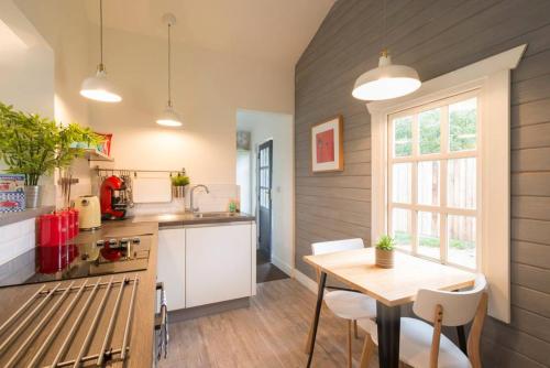 uma cozinha com uma mesa de madeira, uma mesa e cadeiras em Walnut Tree Lodge em Aylsham