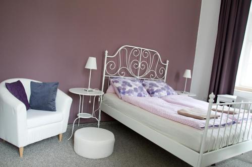 a bedroom with a bed and a white chair at Penzion Zámek Rozsochatec in Rozsochatec