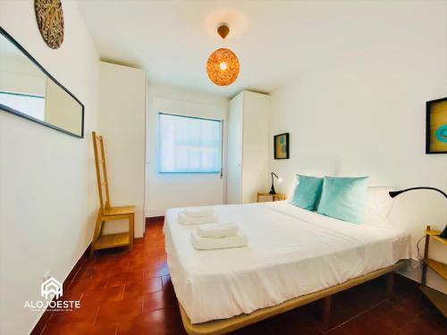 Un dormitorio con una gran cama blanca con almohadas azules. en Água à Vista - Apto com 2 quartos e Piscina, en Ericeira