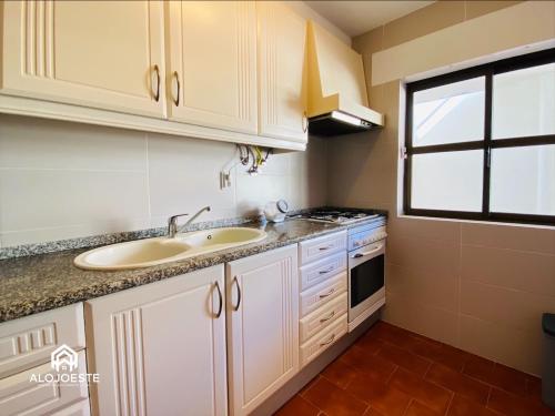 una cocina con fregadero y estufa en Água à Vista - Apto com 2 quartos e Piscina, en Ericeira