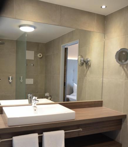 a bathroom with a sink and a mirror at Hotel Bergwirt in Herrieden