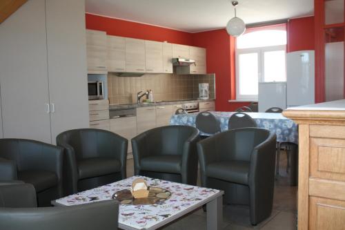 a room with chairs and a table and a kitchen at Gite Prairie Fleurie in Mai Cornet