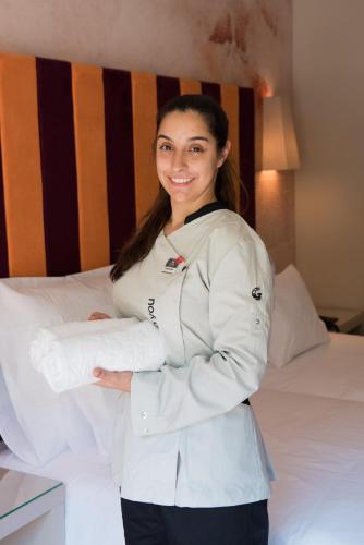 a woman in a white coat standing next to a bed at Vila Gale Serra da Estrela in Manteigas