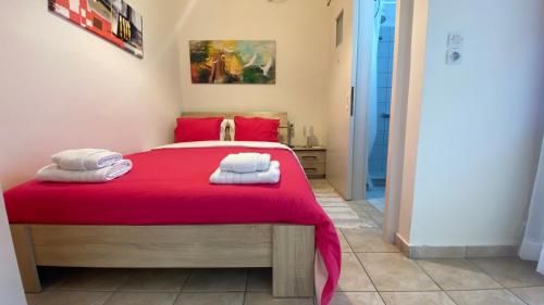 a bedroom with a red bed with towels on it at Patras Port apartment in Patra
