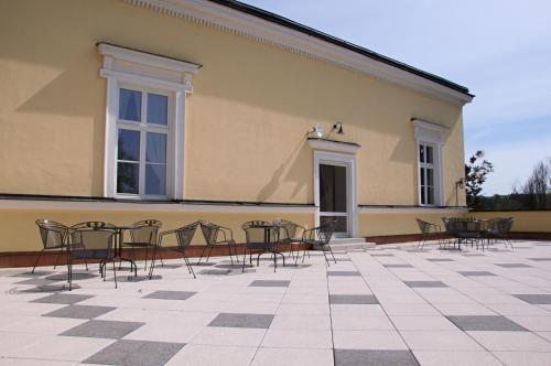a group of chairs and tables in front of a building at Penzion Zámek Rozsochatec in Rozsochatec