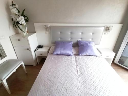 a bedroom with a white bed with purple pillows at Hotel Nordic in Bellaria-Igea Marina