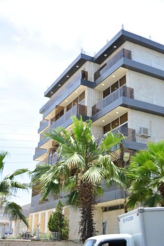 a tall building with palm trees in front of it at Rakeen Hotel in Amman