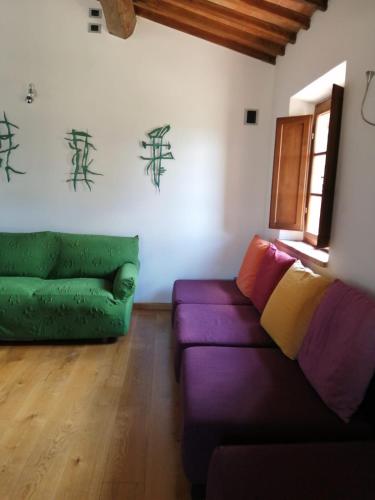 a living room with a purple couch and a green couch at Relais Poggio al Vento in Pomarance
