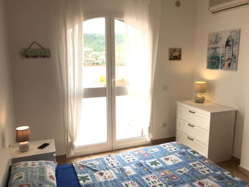 a bedroom with a bed and a dresser and a window at Appartamento Alfea in Porto Santo Stefano