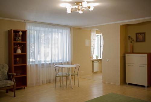 d'un salon avec une table, des chaises et une fenêtre. dans l'établissement Apartments near Gogol theater, à Poltava
