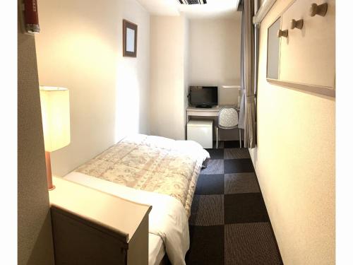a small room with a bed and a desk at Hotel Hashimoto in Sapporo