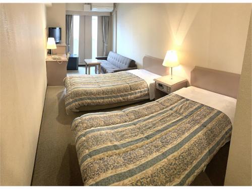 a hotel room with two beds and a couch at Hotel Hashimoto in Sapporo