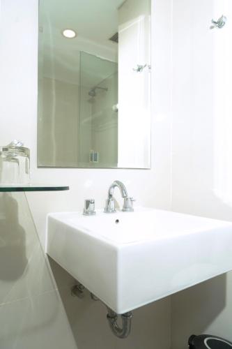 a white bathroom with a sink and a mirror at Lynn Hotel Serang in Serang