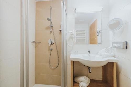 ein Bad mit einem Waschbecken und einer Dusche in der Unterkunft Hotel Silberfux in Sankt Veit im Pongau