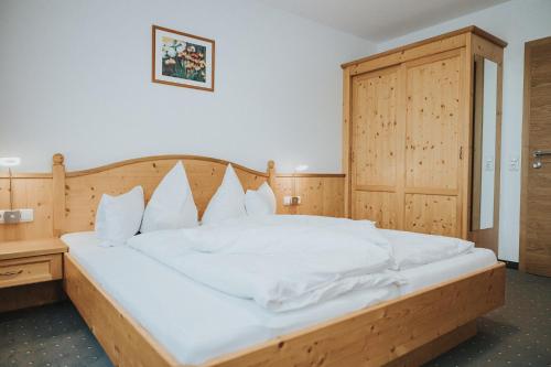 a bedroom with a large white bed with a wooden headboard at Hotel Silberfux in Sankt Veit im Pongau