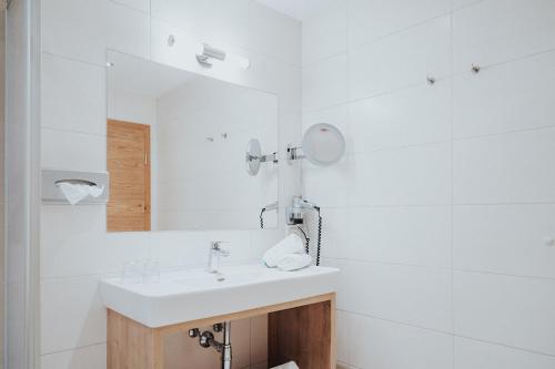 a white bathroom with a sink and a mirror at Hotel Silberfux in Sankt Veit im Pongau