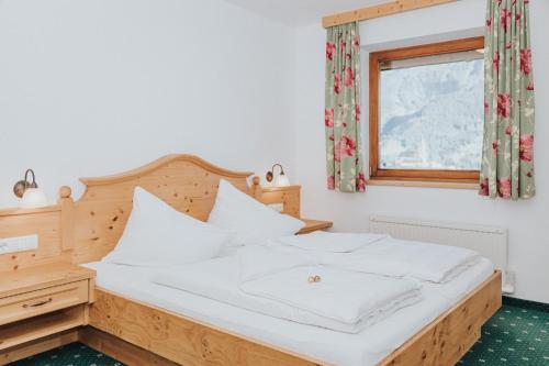 a bedroom with a bed with white sheets and a window at Hotel Silberfux in Sankt Veit im Pongau