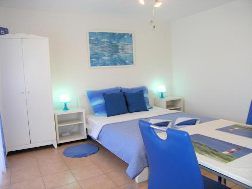 a bedroom with a bed and a table with blue chairs at apartmani Žganec in Baška