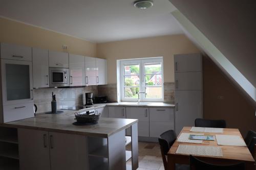 une cuisine avec des placards blancs, une table et une fenêtre dans l'établissement Ferienwohnung Boskop, à Stade