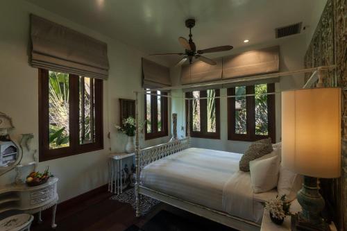 a bedroom with a bed with a ceiling fan and windows at Howie's HomeStay in Mae Rim