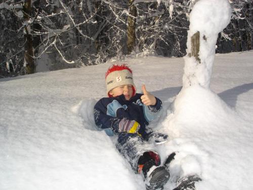 a young child laying in the snow at Bodenhof Ferienwohnungen in Fieberbrunn