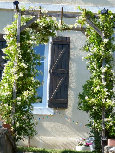 een prieel met een raam en bloemen op een huis bij la maison du lac in Aubin
