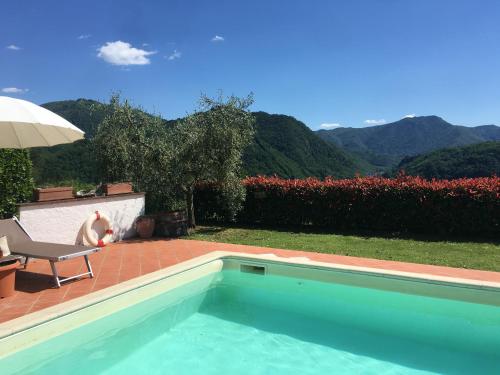 a swimming pool with a chair and an umbrella at Agriturismo Tenuta La Fratta in Bagni di Lucca