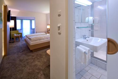 a bathroom with a sink and a bedroom with a bed at Geniesserhotel Alpin GmbH in Achenkirch