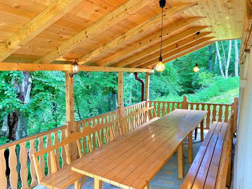 una mesa de madera en un porche con techo de madera en Etno selo Milanovic - Nonac en Kuršumlija