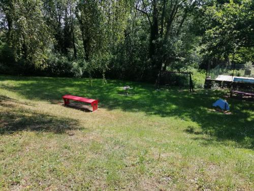 un parque con un banco rojo en el césped en Chalet village vacances en Waulsort