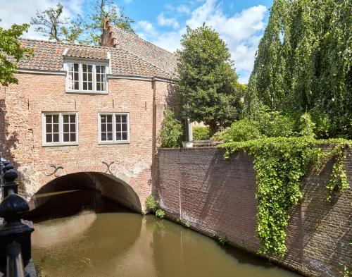 uma ponte sobre um rio em frente a um edifício em The Guest Apartments - Uilenburg em Den Bosch