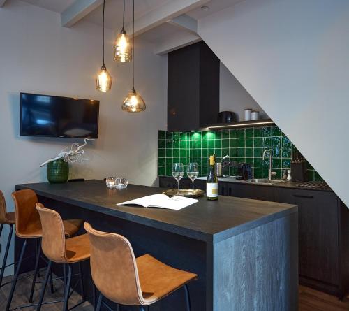 een keuken met een bar met stoelen en een wastafel bij The Guest Apartments - Uilenburg in Den Bosch