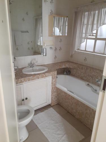 a bathroom with a toilet and a tub and a sink at Hazelonz Bed &Breakfast in Pretoria