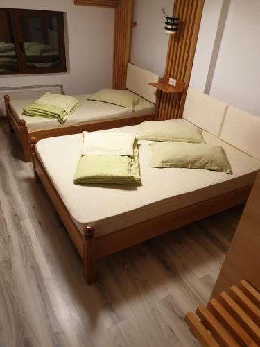 two beds in a room with wooden floors at Motel Mesterul Manole in Curtea de Argeş