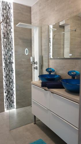 a bathroom with two blue sinks and a shower at GARDENIA BLUE APART Dziwnów z widokiem na morze in Dziwnów