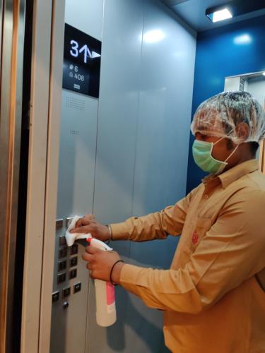 a person wearing a mask putting a bottle in an elevator at Laxmi Palace Heritage Boutique Hotel in Jaipur