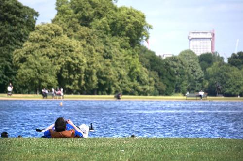 two people laying on the grass near a body of water at Astor Hyde Park Hostel in London