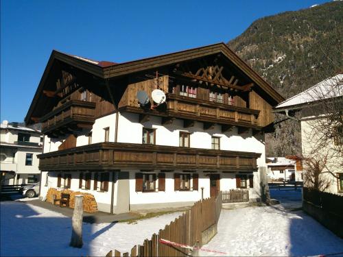 a large wooden building in the snow next to a mountain at Aparts33 in Längenfeld