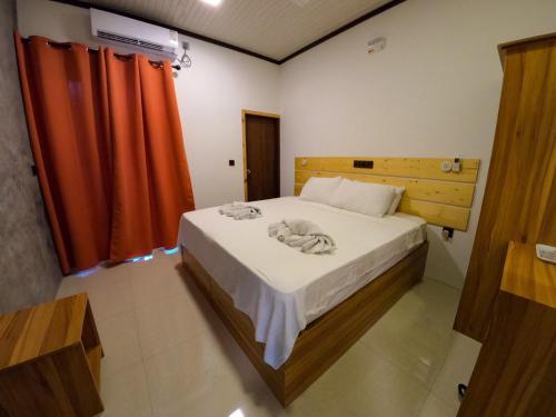 a bedroom with a bed with white sheets and orange curtains at Huvan Inn in Fulidhoo