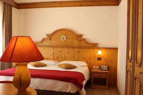 una camera da letto con un letto con una lampada sopra di Hotel Vallée Blanche Courmayeur a Courmayeur