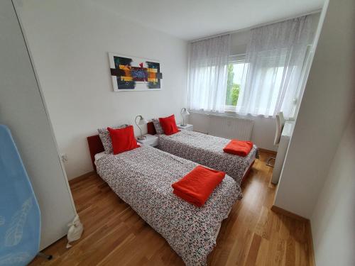 two beds in a small room with red pillows at Apartment Rose in Zagreb