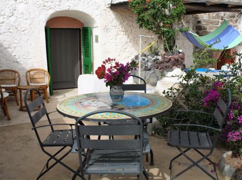 a patio table with chairs and a vase of flowers at Dammusi di Venere - U Locu in Pantelleria