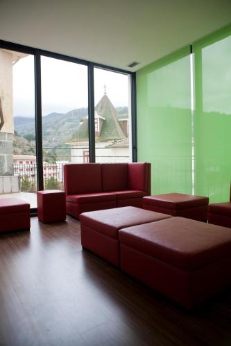 a living room with red furniture and large windows at Hotel Comércio in Resende