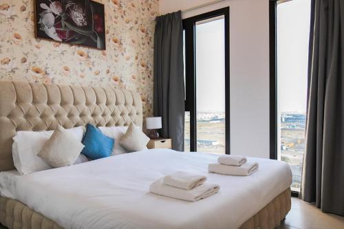 a bedroom with a large white bed with towels on it at SHH - 1BR Apartment in Hayat Boulevard, Townsquare in Dubai