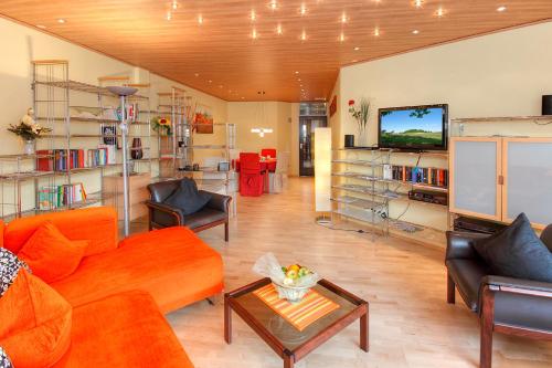 sala de estar con muebles de color naranja y TV de pantalla plana. en Business Suiten, en Bochum