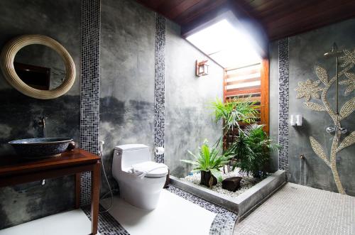 a bathroom with a toilet and plants in it at Maikaew Damnoen Resort in Damnoen Saduak
