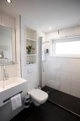 a white bathroom with a toilet and a sink at Hotel zur Post in Brilon